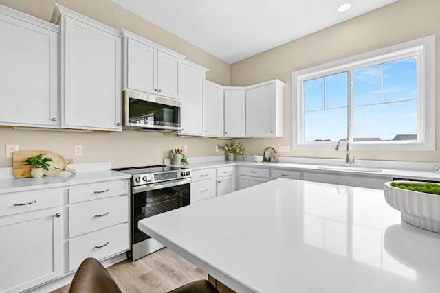 1382 Prairie Creek Cir Unit 15D, Oconomowoc, WI 53066 - kitchen with stainless steel appliances, light wood-type flooring, white cabinets, and light countertops
