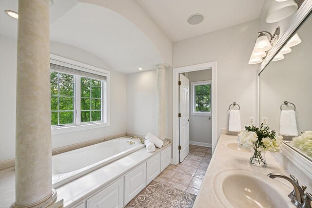 1706 Ashlawn Ln, Waunakee, WI 53597 - full bath featuring decorative columns, a bath, double vanity, and vaulted ceiling