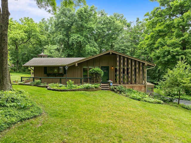 2831 N Wildwood Dr, Lake Geneva, WI 53147 - view of front of home featuring a front lawn, board and batten siding, a forest view, and covered porch