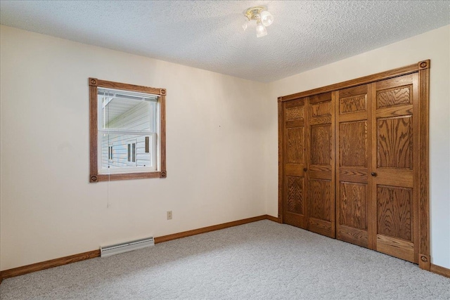 7269 County Road V, Marshfield, WI 54449 - unfurnished bedroom with baseboard heating, light colored carpet, a textured ceiling, and a closet