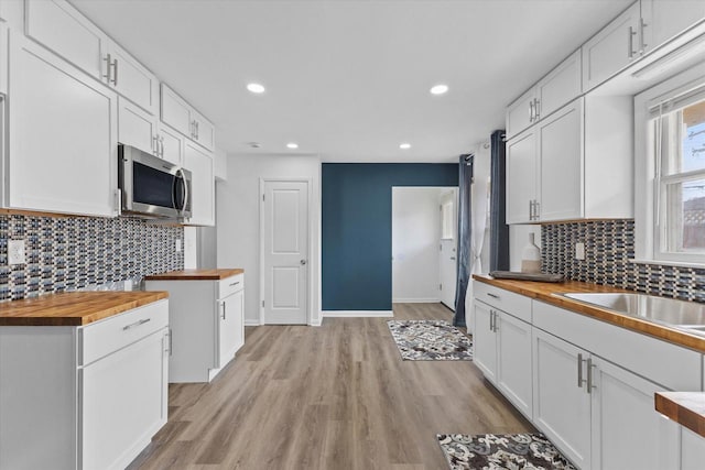 8122 W Potomac Ave, Milwaukee, WI 53218 - kitchen featuring butcher block counters, stainless steel microwave, tasteful backsplash, and recessed lighting