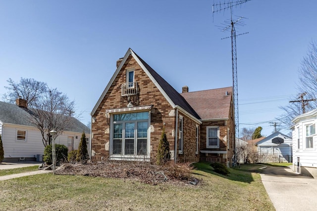 7414 5th Ave, Kenosha, WI 53143 - tudor house with brick siding, a chimney, a shingled roof, and a front lawn