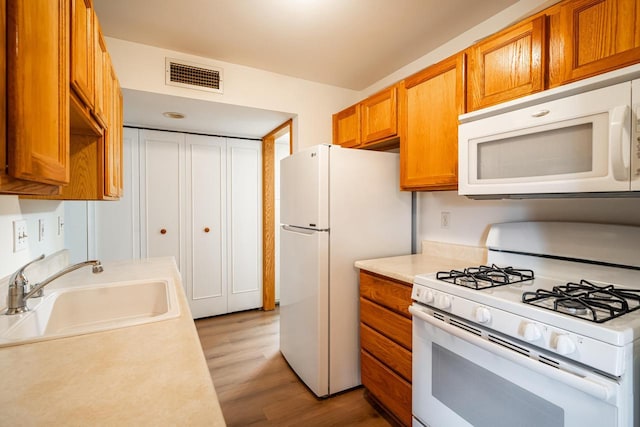 11957 N Appleton Ave Unit 19, Milwaukee, WI 53224 - kitchen featuring white appliances, light countertops, light wood-style floors, and brown cabinets