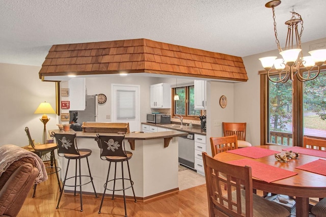 1167 Tee Trl, Nekoosa, WI 54457 - kitchen featuring appliances with stainless steel finishes, white cabinetry, a peninsula, light wood-style floors, and a kitchen breakfast bar