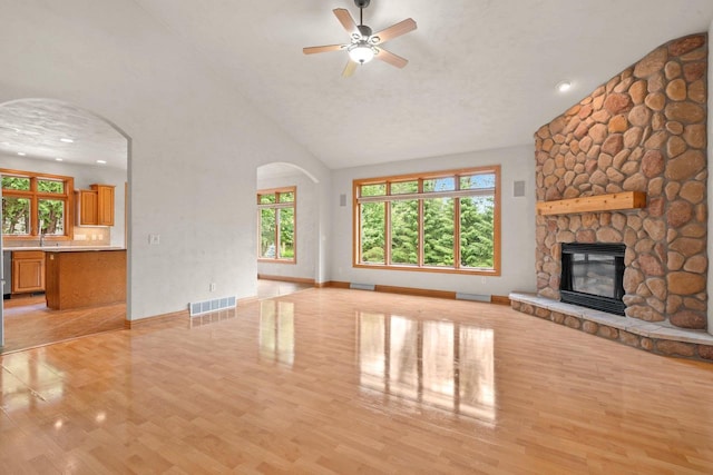 N3520 Range Ct, Freedom, WI 54913 - unfurnished living room featuring light wood finished floors, ceiling fan, high vaulted ceiling, arched walkways, and a fireplace