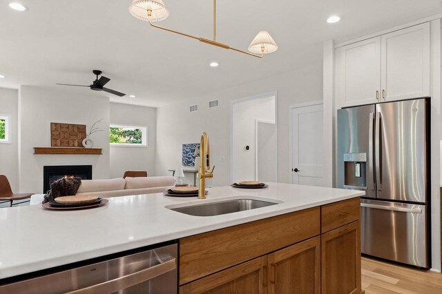 1108 Heritage Ct, Waunakee, WI 53597 - kitchen featuring appliances with stainless steel finishes, open floor plan, light countertops, recessed lighting, and a lit fireplace