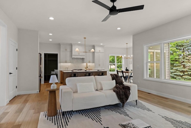 1108 Heritage Ct, Waunakee, WI 53597 - living room featuring a ceiling fan, light wood finished floors, a chandelier, and recessed lighting
