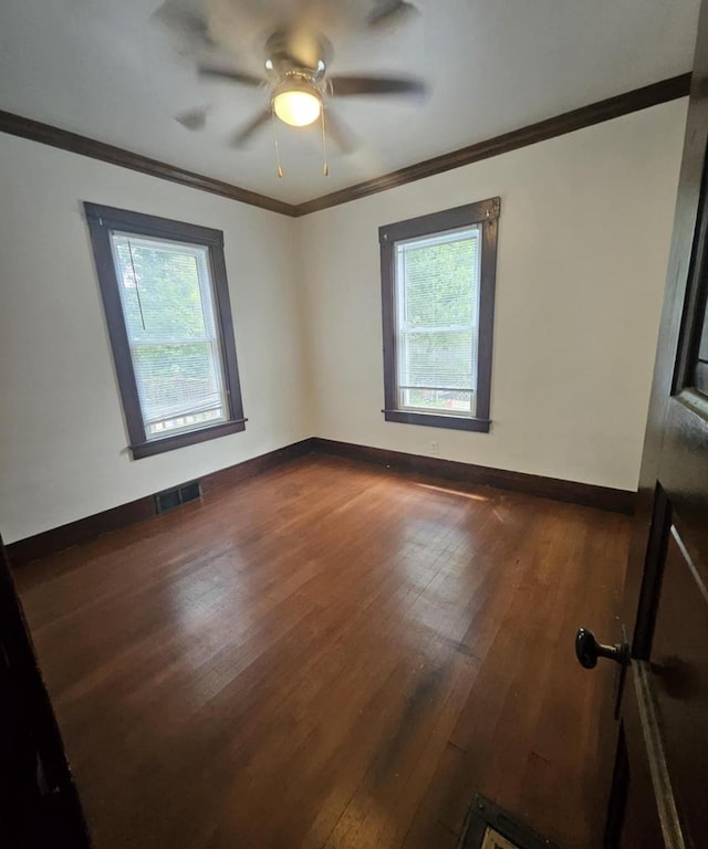 spare room featuring dark wood-type flooring, plenty of natural light, ornamental molding, and ceiling fan