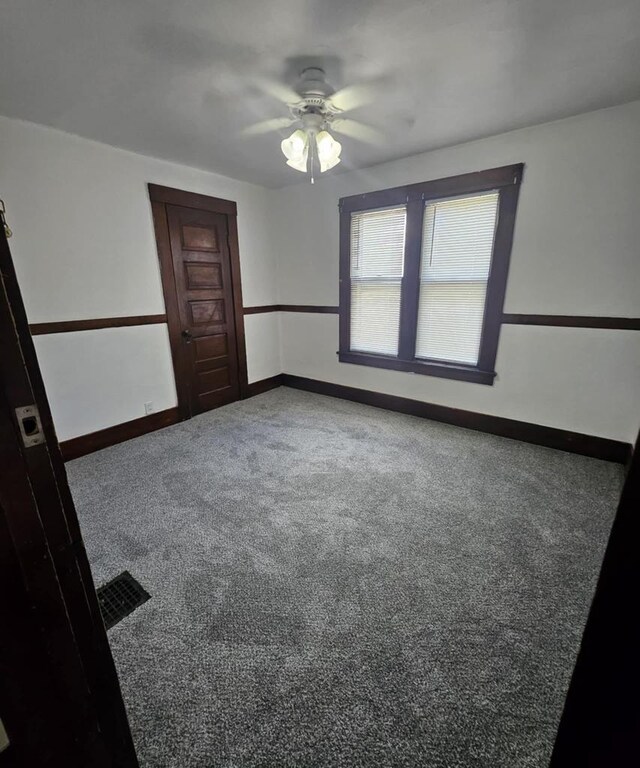 carpeted spare room with ceiling fan and baseboards