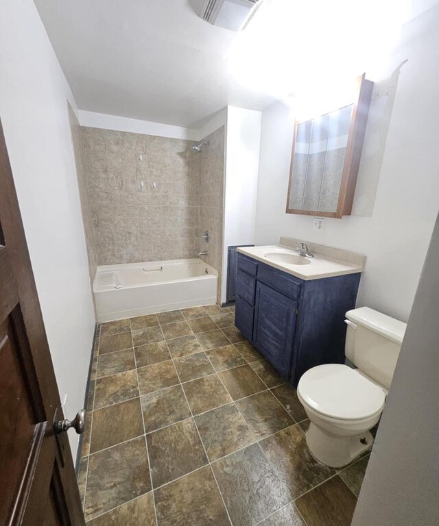 full bath featuring vanity, washtub / shower combination, and stone finish floors