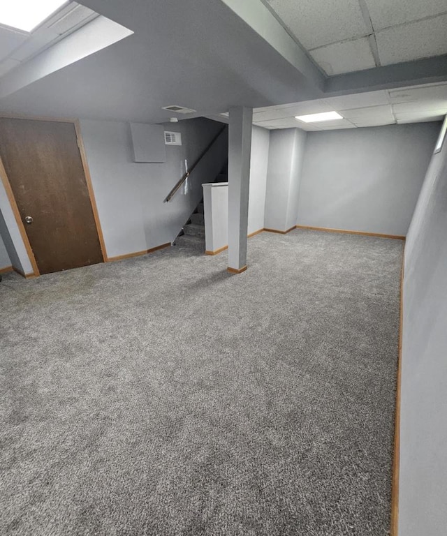 finished basement featuring carpet flooring, stairway, and a paneled ceiling