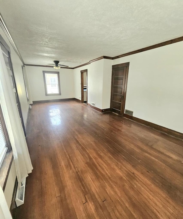 empty room featuring a textured ceiling, a ceiling fan, crown molding, and dark wood-style flooring