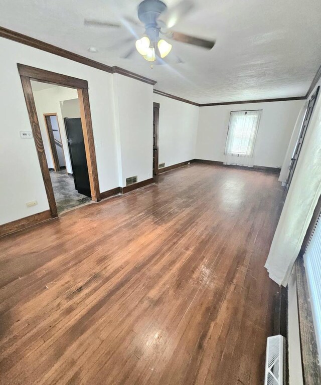 empty room with ceiling fan, wood finished floors, and crown molding