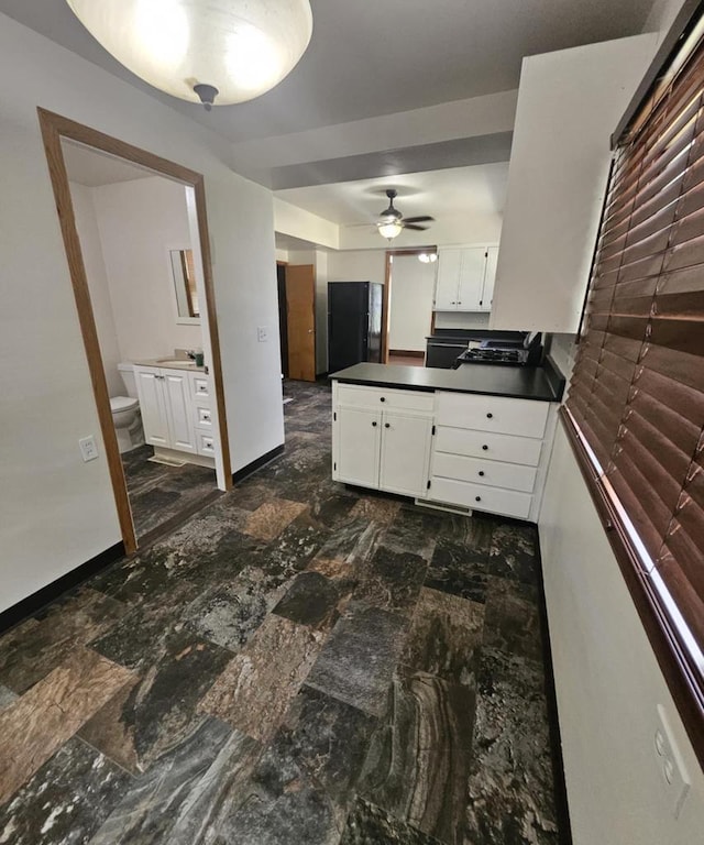 kitchen with white cabinetry, dark countertops, a ceiling fan, and a peninsula