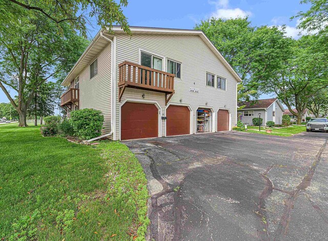 241 Bayberry Ln, Fond Du Lac, WI 54935 - view of side of property featuring a garage, asphalt driveway, a yard, and a balcony