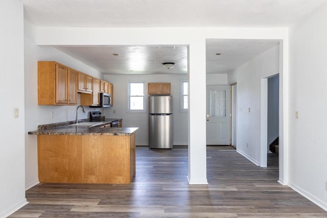 524 W New York Ave, Oshkosh, WI 54901 - kitchen with stainless steel appliances, a peninsula, dark countertops, and dark wood-style flooring
