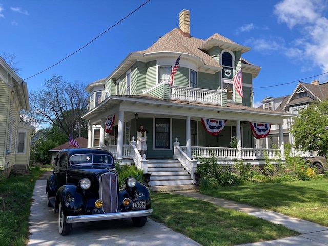 1133 Algoma Blvd, Oshkosh, WI 54901 - victorian home with covered porch, a chimney, a front lawn, and roof with shingles