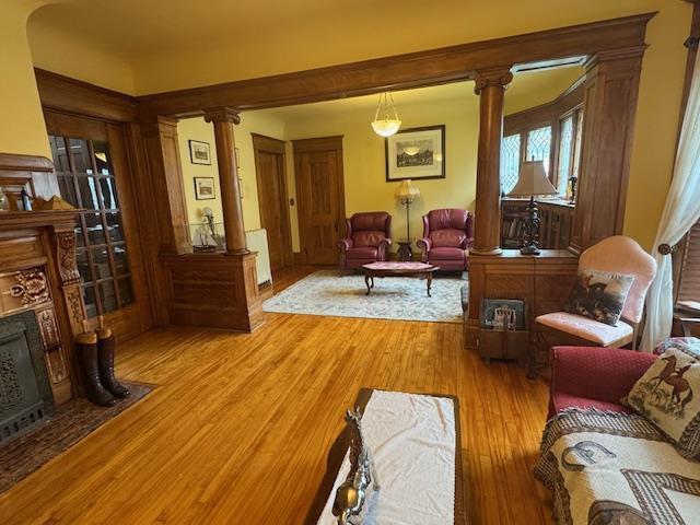 1133 Algoma Blvd, Oshkosh, WI 54901 - living area featuring ornate columns, light wood-style floors, a fireplace, and radiator heating unit