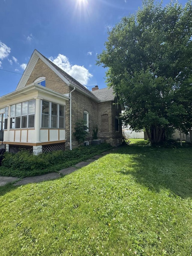 208 N 5th St, Watertown, WI 53094 - view of side of home with a sunroom, a lawn, a chimney, and brick siding