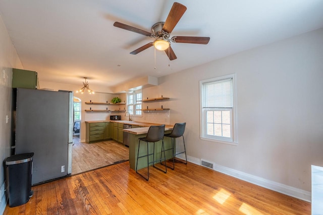 7550 26th Ave, Kenosha, WI 53143 - kitchen with green cabinetry, stainless steel appliances, open shelves, light wood-type flooring, and light countertops