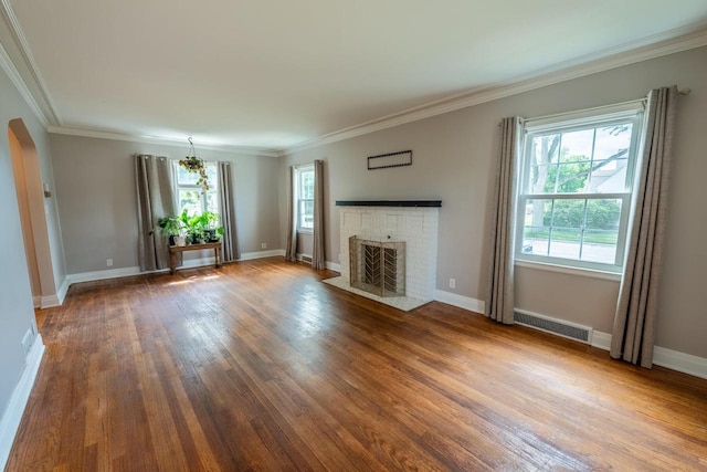 7550 26th Ave, Kenosha, WI 53143 - unfurnished living room featuring wood finished floors, healthy amount of natural light, a brick fireplace, crown molding, and arched walkways
