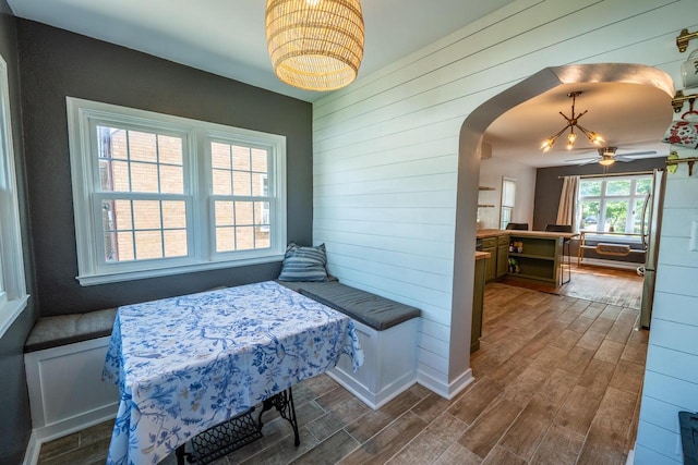 7550 26th Ave, Kenosha, WI 53143 - dining area featuring wood finished floors, a chandelier, wooden walls, and arched walkways