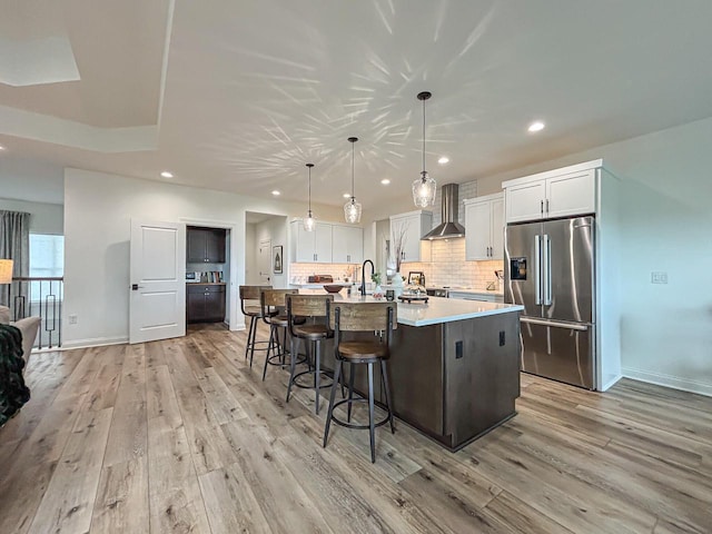 1601 Sauk Trl, Waukesha, WI 53189 - kitchen with stainless steel fridge, light wood-style floors, wall chimney range hood, light countertops, and recessed lighting