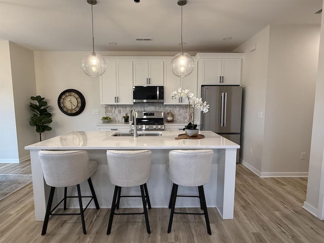 3150 Bartells Dr, Beloit, WI 53511 - kitchen with stainless steel appliances, white cabinetry, light wood finished floors, and backsplash
