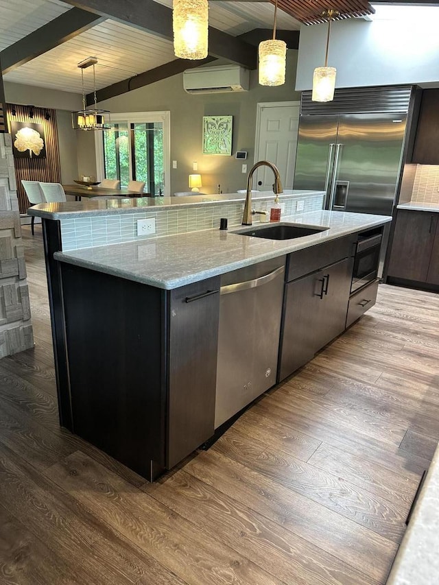 8221 Fairmont Ln, Greendale, WI 53129 - kitchen with stainless steel appliances, beam ceiling, a wall unit AC, an island with sink, and pendant lighting