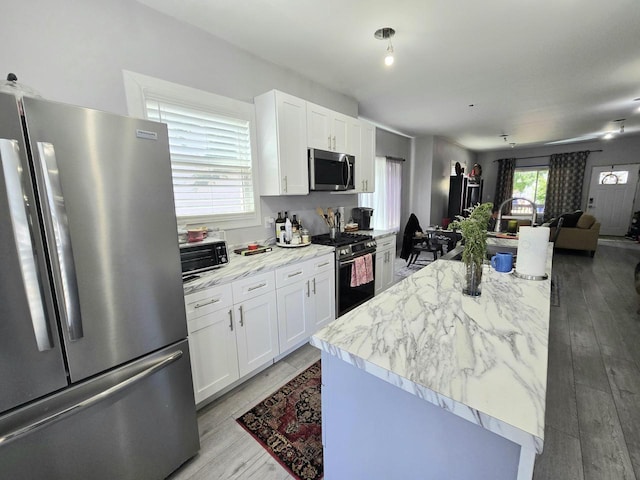 1635 Grand Ave, Racine, WI 53403 - kitchen with appliances with stainless steel finishes, white cabinetry, light wood-type flooring, and a kitchen island