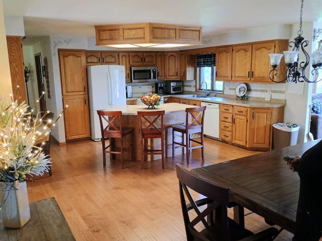 N1894 Vandenbroek Rd, Kaukauna, WI 54130 - kitchen with white appliances, a chandelier, light countertops, brown cabinets, and light wood-style flooring