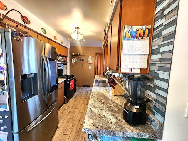 5100 16th St, Racine, WI 53406 - kitchen with stainless steel refrigerator with ice dispenser, black gas stove, light wood-style floors, light countertops, and brown cabinetry