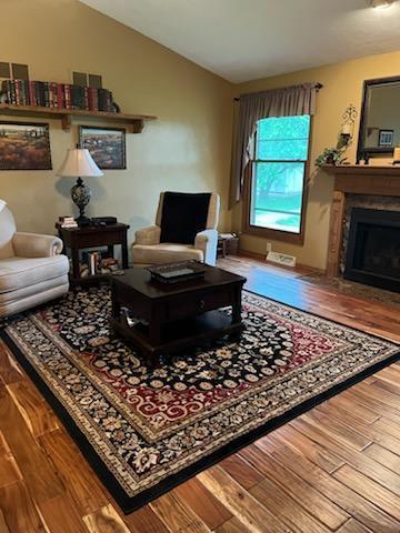 2309 E Pine Tree Ct, Milton, WI 53563 - living room featuring wood finished floors, lofted ceiling, and a fireplace with flush hearth