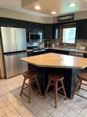 2309 E Pine Tree Ct, Milton, WI 53563 - kitchen featuring appliances with stainless steel finishes, a kitchen breakfast bar, recessed lighting, dark cabinetry, and light tile patterned floors
