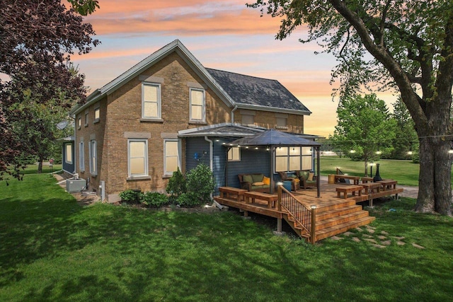 N5562 County Road A, Lake Mills, WI 53551 - back of house at dusk with a wooden deck, a yard, brick siding, and an outdoor living space