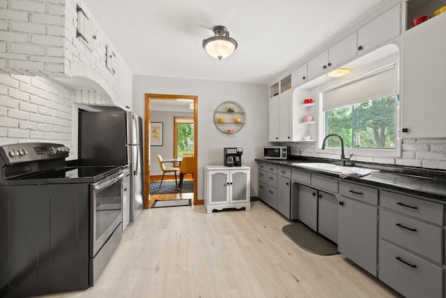 1240 Franklin St, Wisconsin Rapids, WI 54494 - kitchen with stainless steel appliances, dark countertops, gray cabinets, light wood-type flooring, and decorative backsplash