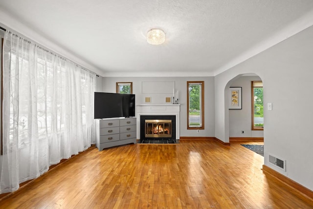 1240 Franklin St, Wisconsin Rapids, WI 54494 - unfurnished living room with arched walkways, light wood-style flooring, and a tiled fireplace