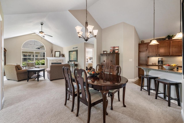 1040 Ann Marie Way, Oconomowoc, WI 53066 - dining room featuring light carpet, a ceiling fan, a fireplace, high vaulted ceiling, and a chandelier