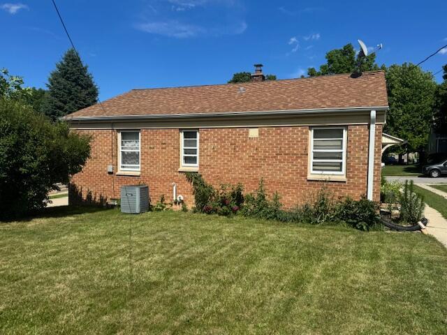 3681 S 5th St, Milwaukee, WI 53207 - back of house featuring a lawn, brick siding, and a shingled roof