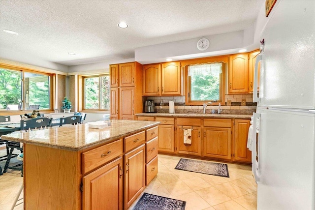 1051 Kings Way, Nekoosa, WI 54457 - kitchen featuring freestanding refrigerator, plenty of natural light, a textured ceiling, backsplash, and a center island