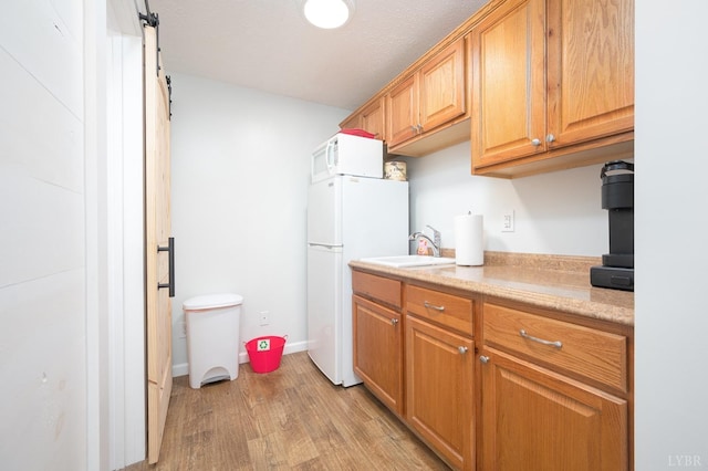 7505 Timberlake Rd, Lynchburg, VA 24502 - kitchen with white appliances, light wood-style floors, light countertops, a barn door, and a sink