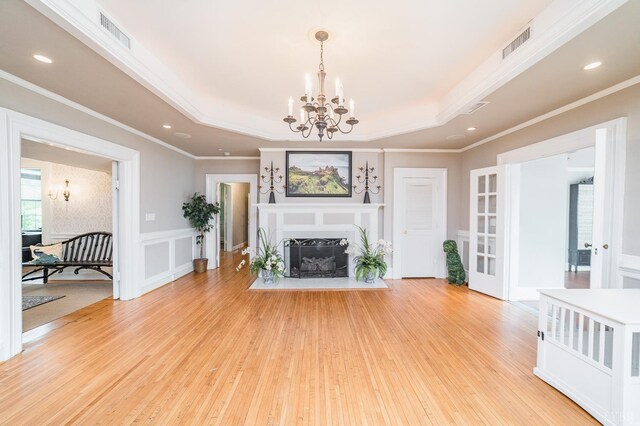 7821 Bellevue Rd, Forest, VA 24551 - unfurnished living room featuring a chandelier, a raised ceiling, light wood-style floors, a wainscoted wall, and crown molding