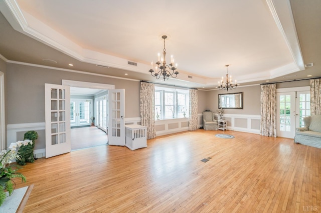 7821 Bellevue Rd, Forest, VA 24551 - unfurnished living room with french doors, a tray ceiling, a chandelier, light wood-style flooring, and ornamental molding