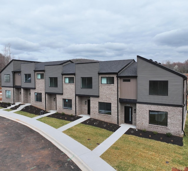 multi unit property with a front lawn and brick siding