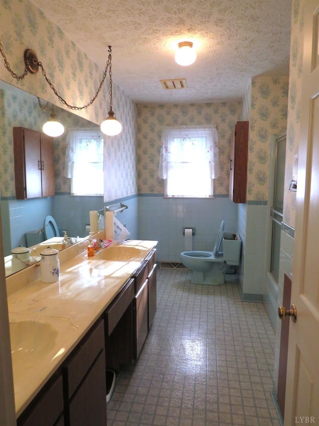 11420 Wards Rd, Rustburg, VA 24588 - bathroom featuring wallpapered walls, wainscoting, toilet, double vanity, and bath / shower combo with glass door