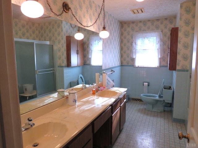 11420 Wards Rd, Rustburg, VA 24588 - bathroom featuring wallpapered walls, wainscoting, a stall shower, double vanity, and toilet