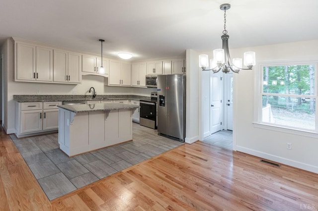 465 Soybean Dr, Appomattox, VA 24522 - kitchen featuring stainless steel appliances, light wood-style flooring, a chandelier, a sink, and a breakfast bar
