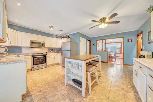 kitchen featuring ceiling fan, appliances with stainless steel finishes, crown molding, light tile patterned flooring, and sink