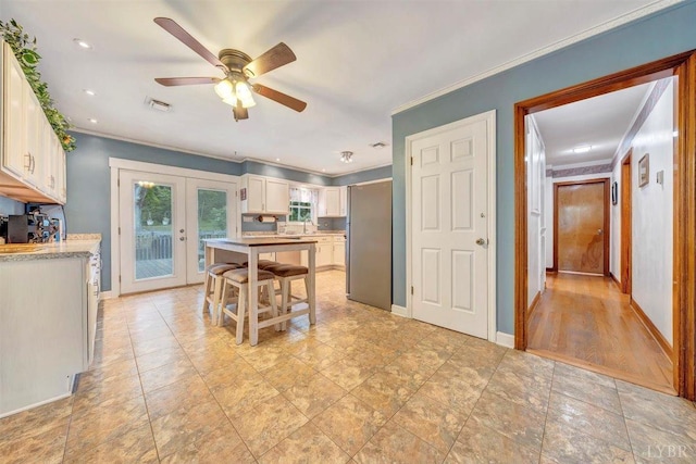 kitchen featuring ceiling fan, light wood-type flooring, crown molding, and white cabinetry