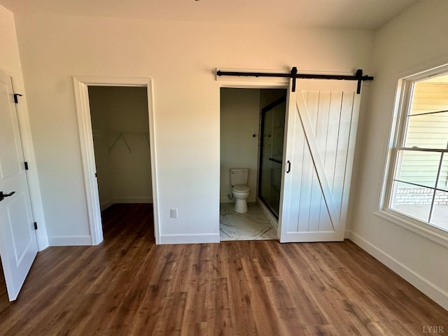 4678 Wildway Rd, Appomattox, VA 24522 - unfurnished bedroom with wood finished floors, baseboards, a walk in closet, and a barn door